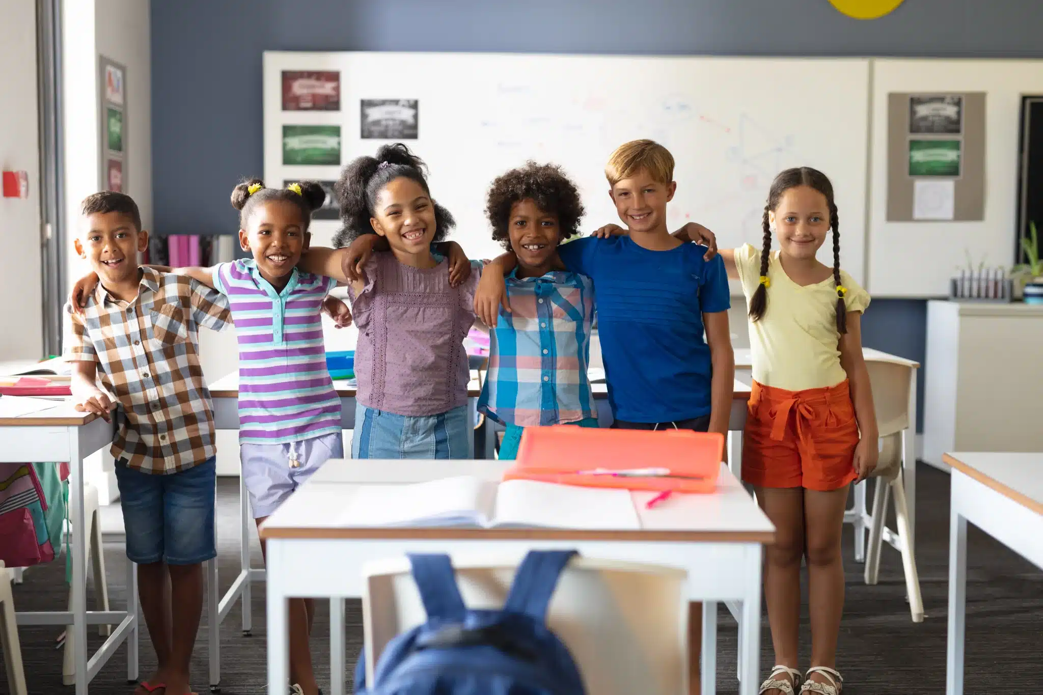 Children standing together behind classroom desks