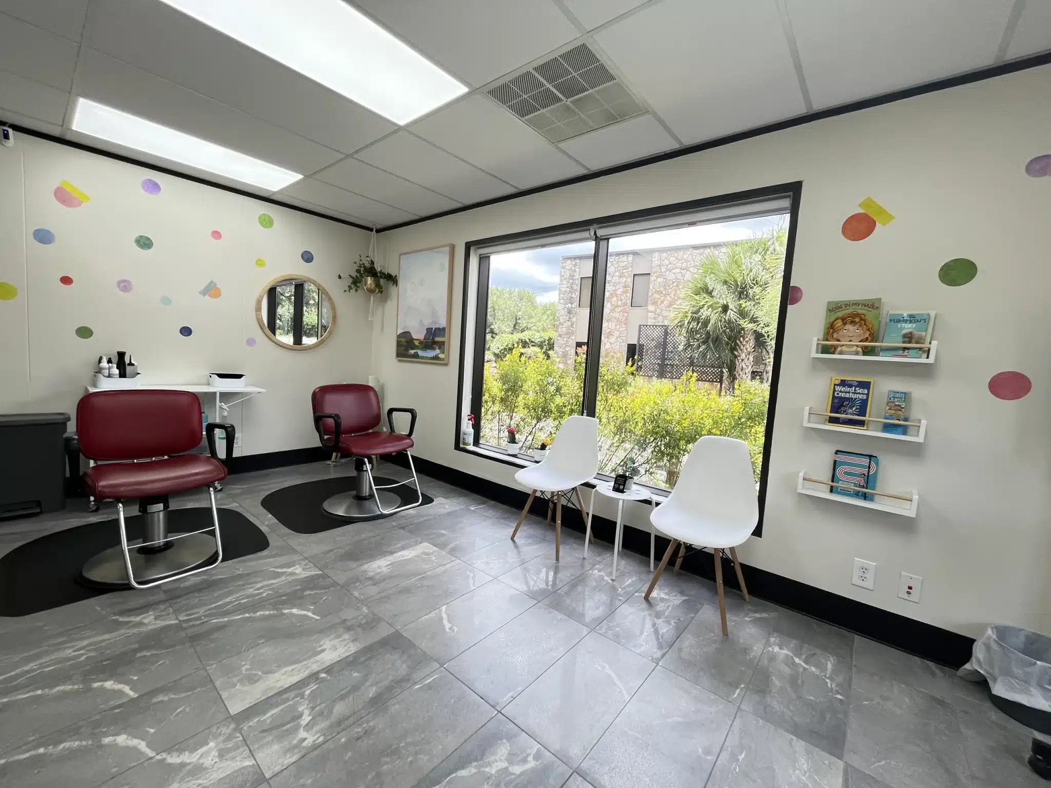 Burgundy salon chairs and white seating in a room with colorful wall dots