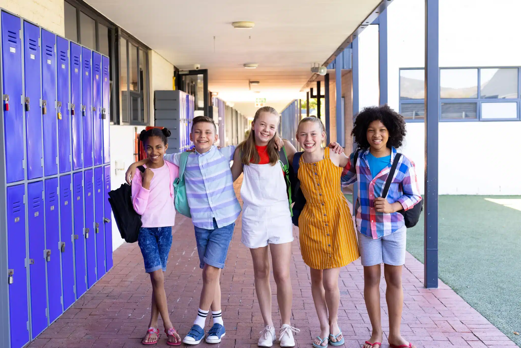 Children with backpacks standing beside purple school lockers