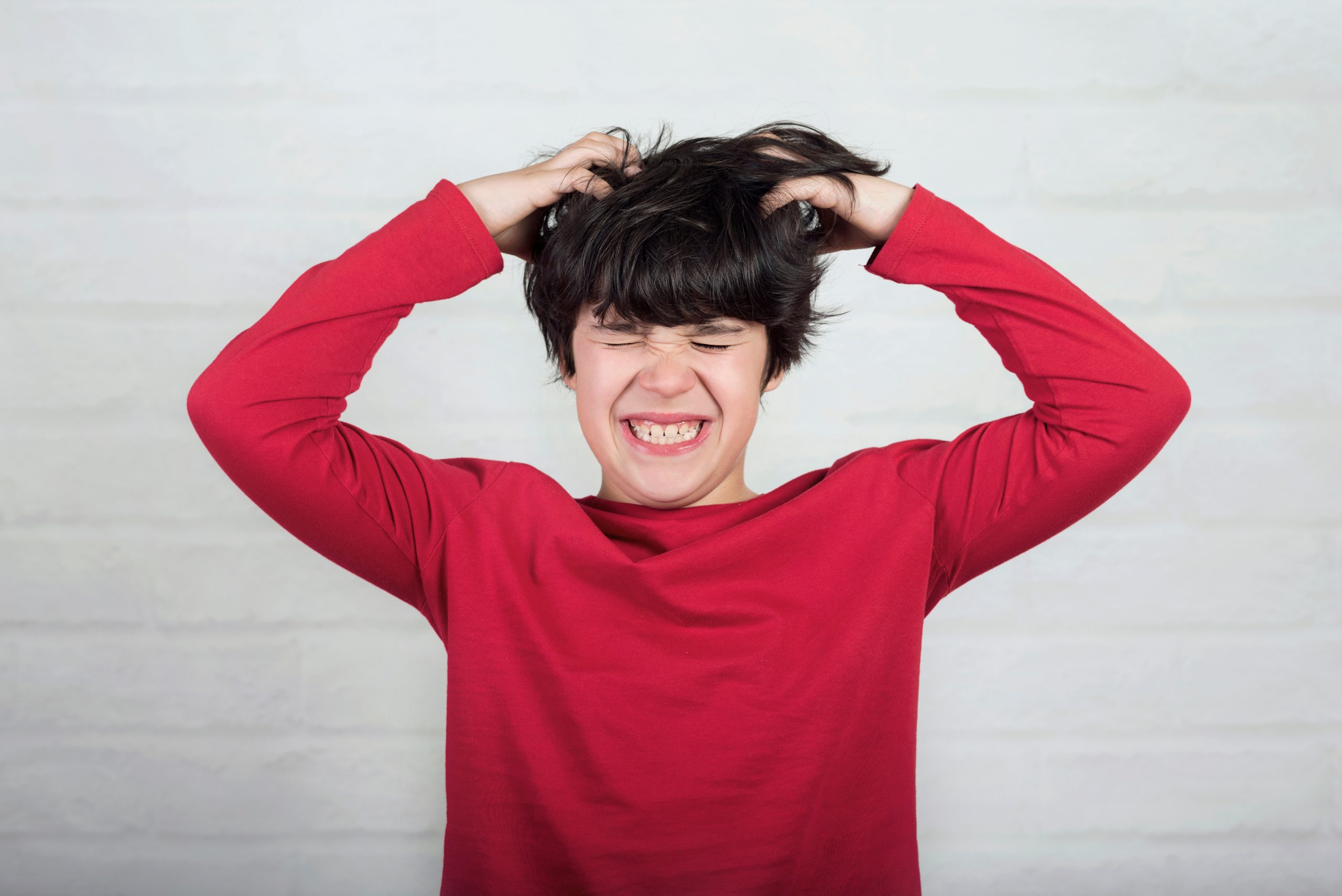 Young boy with short hair scratching the back of his head, the early sign of a lice infestation