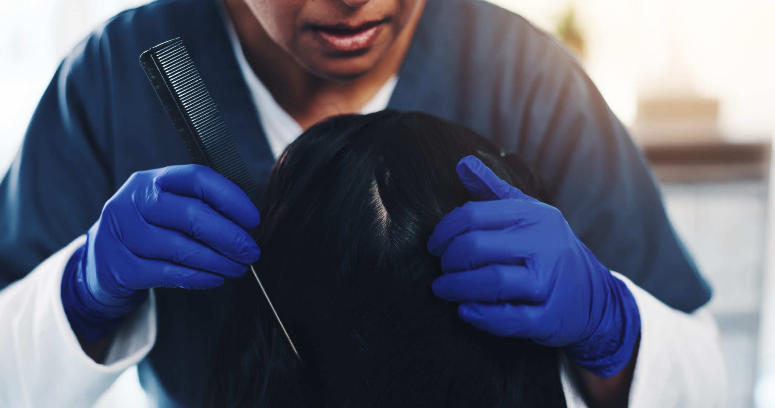 A young child's hair and scalp being gently checked and treated for lice by a professional technician.