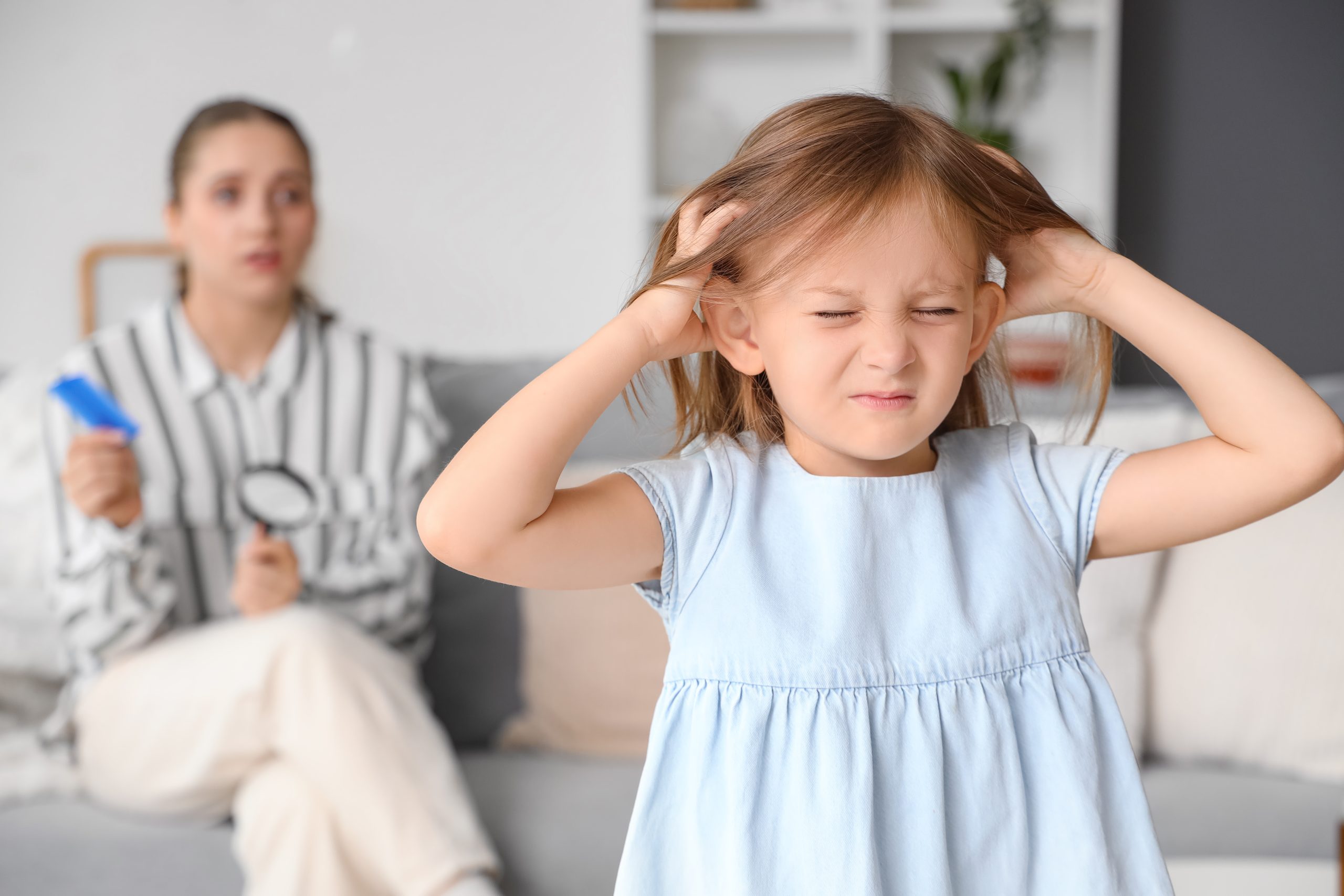 Young child scratching an itchy head at home from an untreated lice case