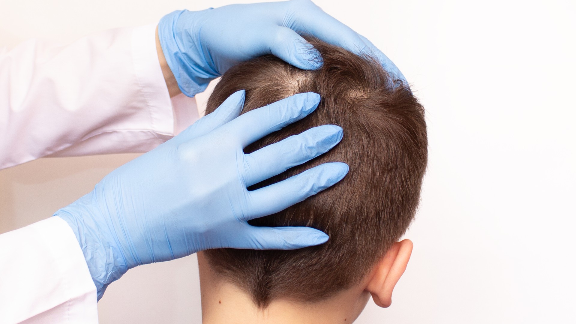 Pediatric professional examining a child scalp for head lice, for Austin pediatrician head lice advice article