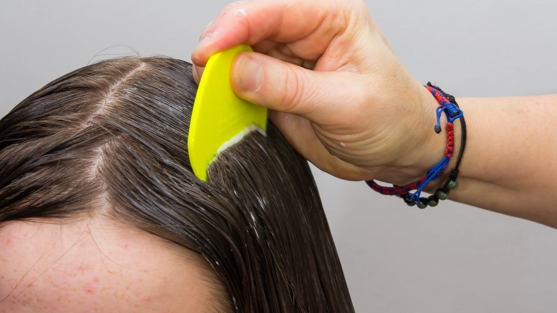Hand combing parted dark hair with a yellow comb